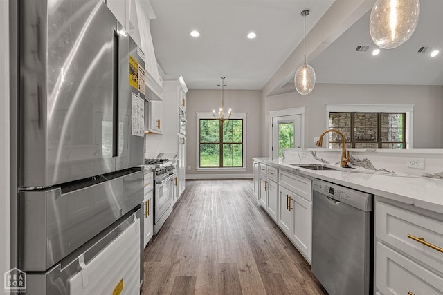 kitchen with hanging light fixtures, white cabinets, visible vents, appliances with stainless steel finishes, and wood finished floors