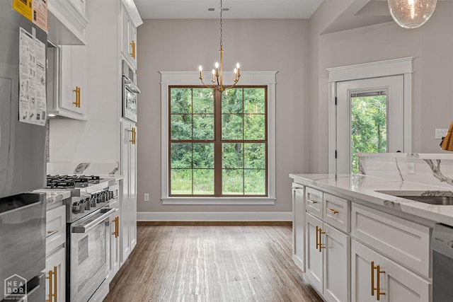 kitchen with stainless steel appliances, white cabinetry, an inviting chandelier, and a healthy amount of sunlight