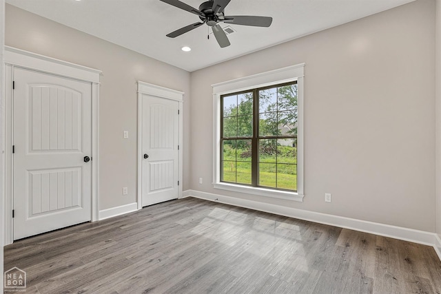 unfurnished bedroom with multiple windows, baseboards, and wood finished floors