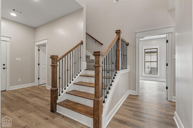 stairs with wood finished floors, baseboards, visible vents, and recessed lighting