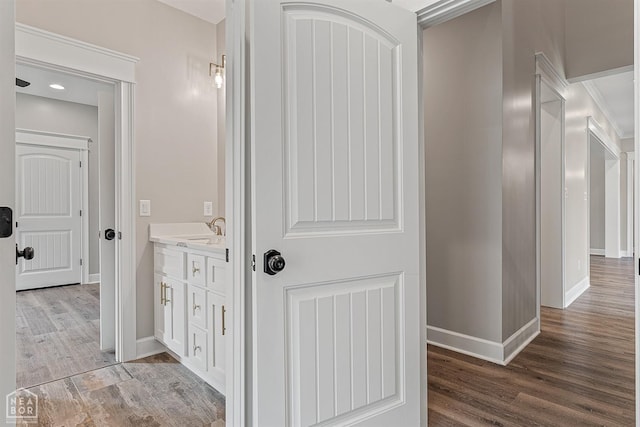 hallway with a sink, baseboards, and light wood-style floors