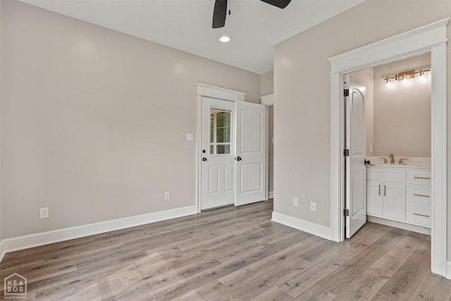 unfurnished bedroom featuring light wood-type flooring, baseboards, and connected bathroom