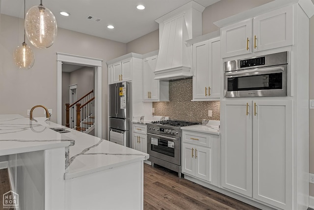 kitchen with visible vents, appliances with stainless steel finishes, premium range hood, wood finished floors, and decorative backsplash