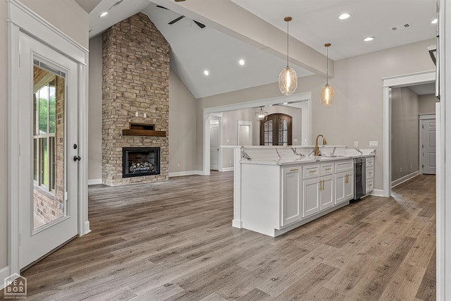 kitchen featuring visible vents, a sink, open floor plan, a stone fireplace, and wine cooler