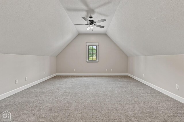 bonus room with baseboards, a textured ceiling, lofted ceiling, carpet, and ceiling fan