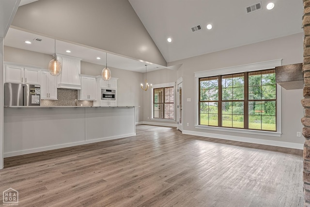kitchen with custom exhaust hood, white cabinetry, visible vents, stainless steel appliances, and wood finished floors