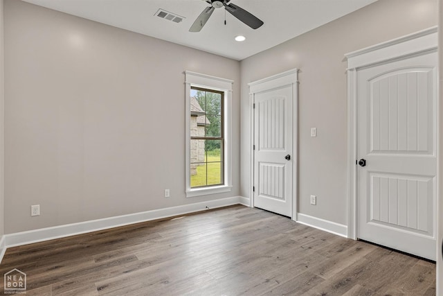 unfurnished bedroom with ceiling fan, visible vents, baseboards, and wood finished floors