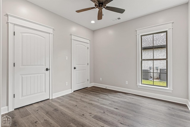 unfurnished bedroom featuring visible vents, baseboards, multiple windows, and wood finished floors