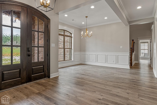 foyer entrance with a decorative wall, ornamental molding, a chandelier, recessed lighting, and wood finished floors