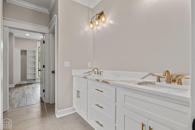 full bath with baseboards, a sink, ornamental molding, double vanity, and wood finished floors