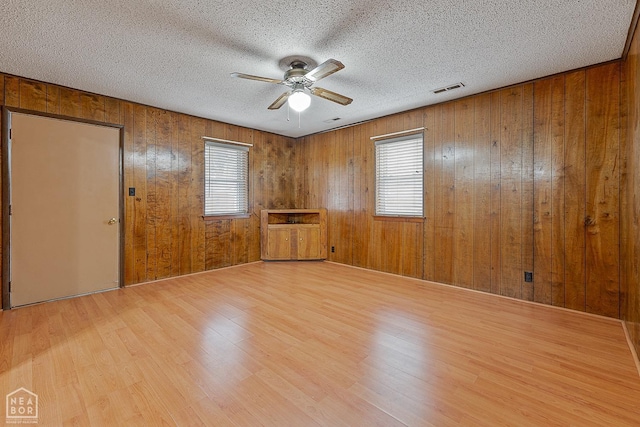 319 Stephans Ln, Corning, AR 72422 - spare room featuring ceiling fan, light wood-style floors, healthy amount of natural light, wood walls, and a textured ceiling