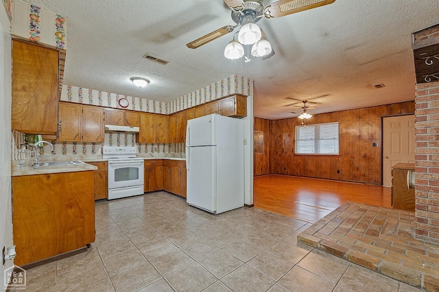 319 Stephans Ln, Corning, AR 72422 - kitchen featuring white appliances, a ceiling fan, under cabinet range hood, brown cabinetry, and a sink