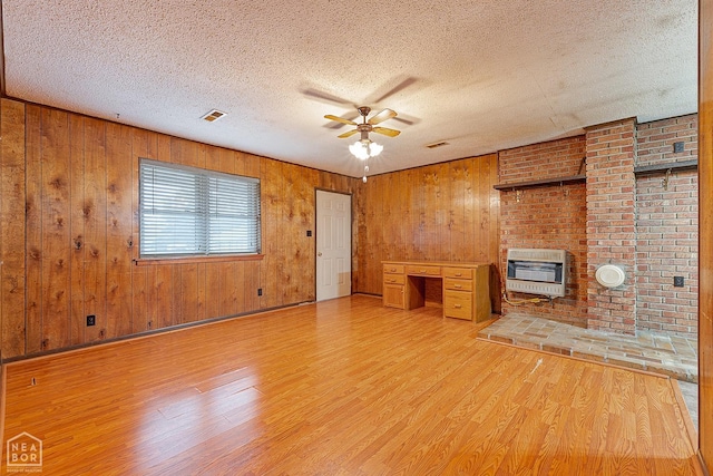 319 Stephans Ln, Corning, AR 72422 - unfurnished living room featuring heating unit, light wood-style floors, a textured ceiling, a ceiling fan, and wood walls