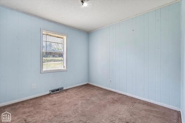 carpeted spare room featuring visible vents and a textured ceiling