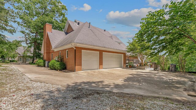 15 Plantation Oaks Ln, Jonesboro, AR 72401 - view of side of property featuring brick siding, a chimney, a garage, roof with shingles, and driveway