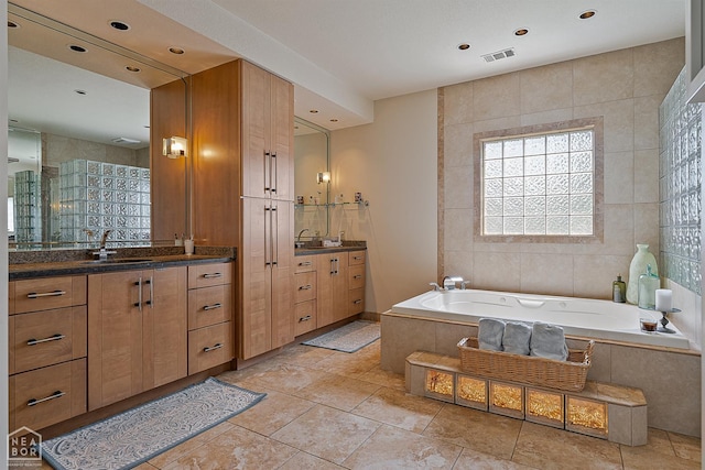 15 Plantation Oaks Ln, Jonesboro, AR 72401 - full bathroom featuring two vanities, a garden tub, recessed lighting, and tile walls