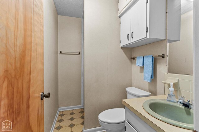 815 NW 3rd St, Walnut Ridge, AR 72476 - bathroom with a textured ceiling, vanity, toilet, tile patterned floors, and baseboards