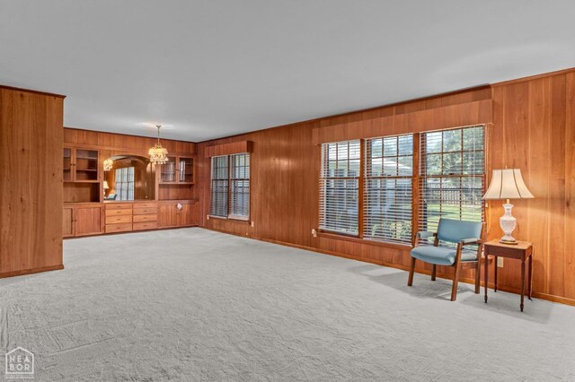 815 NW 3rd St, Walnut Ridge, AR 72476 - unfurnished living room featuring wooden walls, a notable chandelier, baseboards, and carpet floors