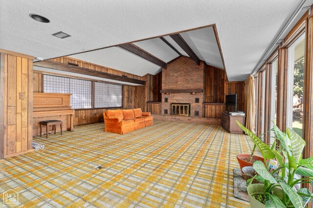 815 NW 3rd St, Walnut Ridge, AR 72476 - unfurnished living room with a textured ceiling, wooden walls, lofted ceiling with beams, and a brick fireplace