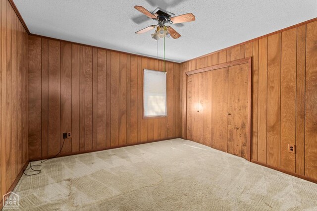 815 NW 3rd St, Walnut Ridge, AR 72476 - empty room with wood walls, a ceiling fan, carpet flooring, and a textured ceiling
