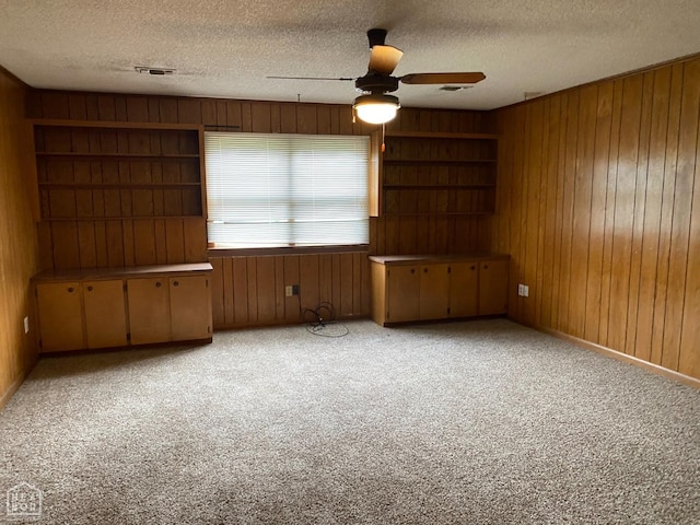 2104 Parkside Dr, Jonesboro, AR 72401 - spare room with wooden walls, light colored carpet, a textured ceiling, a ceiling fan, and visible vents