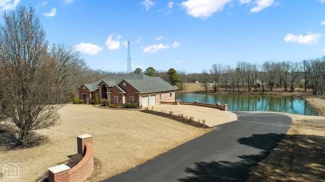 exterior space with driveway, a garage, a boat dock, and a water view