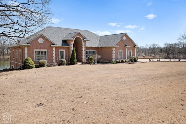 view of front facade featuring brick siding and a shingled roof