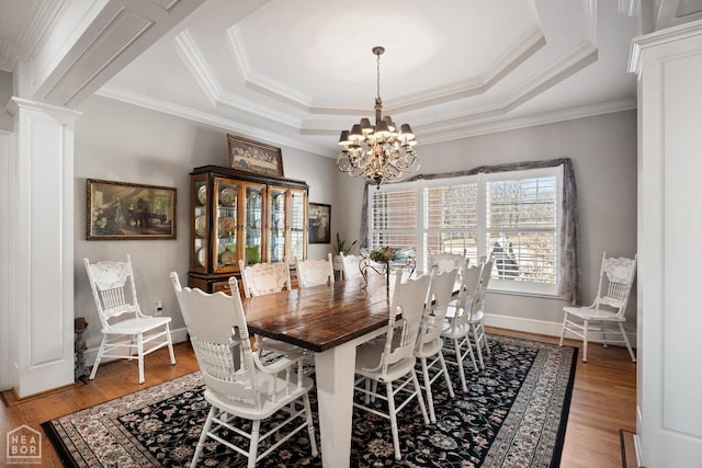 dining room featuring a tray ceiling, a chandelier, and light wood-style flooring