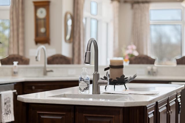details featuring dishwashing machine, light countertops, dark brown cabinets, and a kitchen island