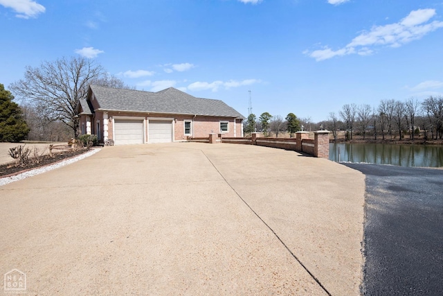 view of side of home featuring a garage, roof with shingles, driveway, and a water view