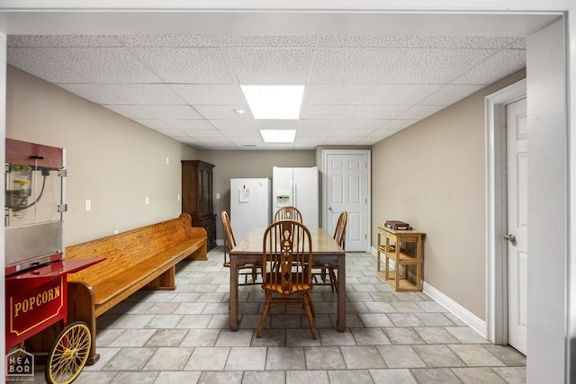 dining area featuring baseboards and a drop ceiling