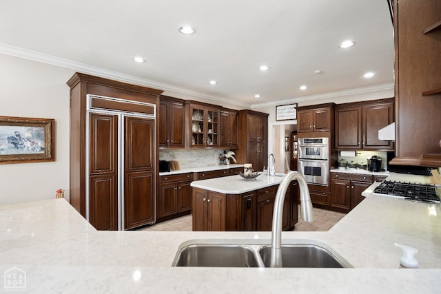 kitchen with stainless steel double oven, a sink, crown molding, and paneled built in refrigerator
