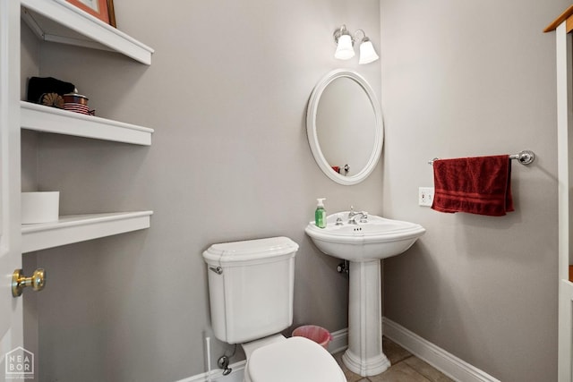 bathroom featuring toilet, a sink, and baseboards