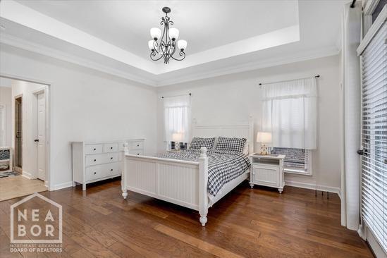 4024 Chapel Hill Dr, Jonesboro, AR 72404 - bedroom with a chandelier, dark wood-type flooring, a raised ceiling, and baseboards