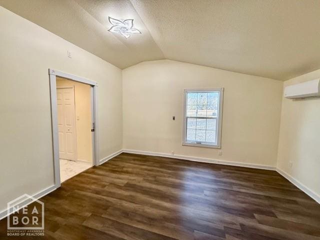 2187 Seagraves Rd, Pocahontas, AR 72455 - empty room with lofted ceiling, dark wood finished floors, a wall unit AC, and a textured ceiling
