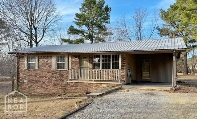 2187 Seagraves Rd, Pocahontas, AR 72455 - ranch-style house featuring an attached carport, a metal roof, gravel driveway, brick siding, and covered porch