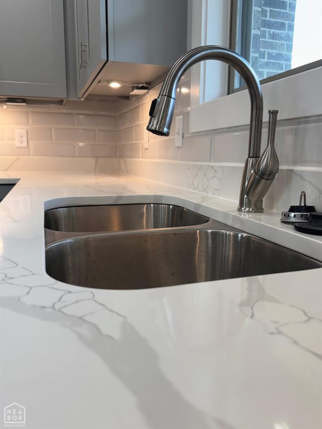 210 E College St, Bono, AR 72416 - kitchen view of a sink, backsplash, and light stone counters
