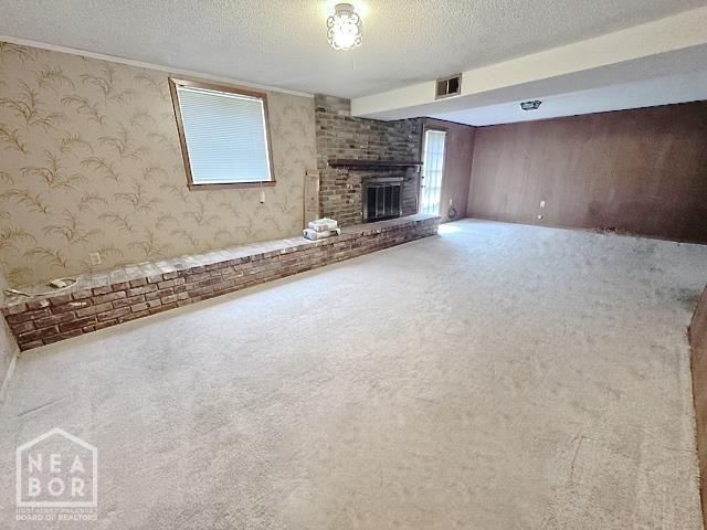 905 Locust Dr, Jonesboro, AR 72401 - unfurnished living room featuring wallpapered walls, a fireplace, a textured ceiling, and carpet