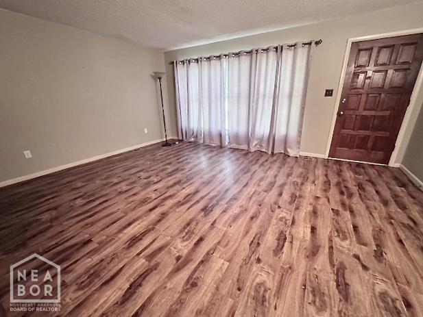 905 Locust Dr, Jonesboro, AR 72401 - unfurnished living room with dark wood finished floors, a textured ceiling, and baseboards