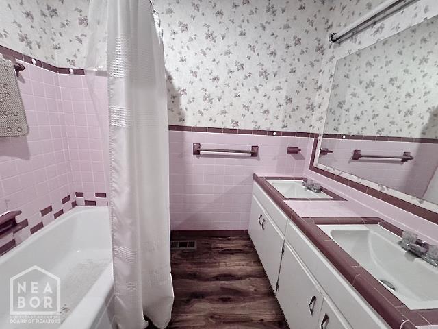 905 Locust Dr, Jonesboro, AR 72401 - full bathroom with wallpapered walls, wood finished floors, wainscoting, tile walls, and double vanity