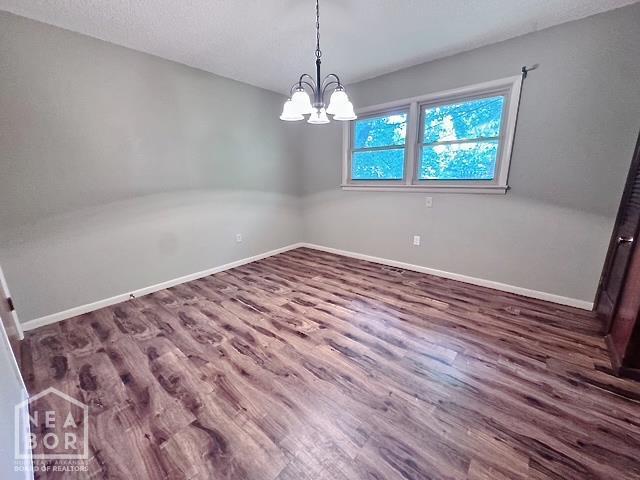 905 Locust Dr, Jonesboro, AR 72401 - unfurnished room with wood finished floors, baseboards, and a chandelier