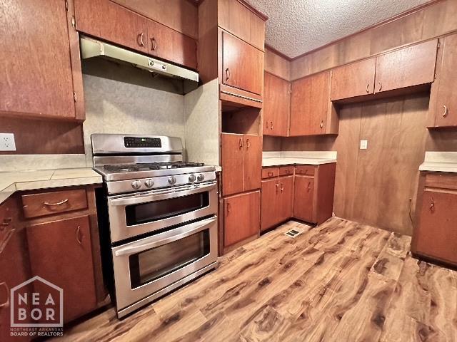 905 Locust Dr, Jonesboro, AR 72401 - kitchen featuring range with two ovens, under cabinet range hood, light wood-type flooring, a textured ceiling, and light countertops