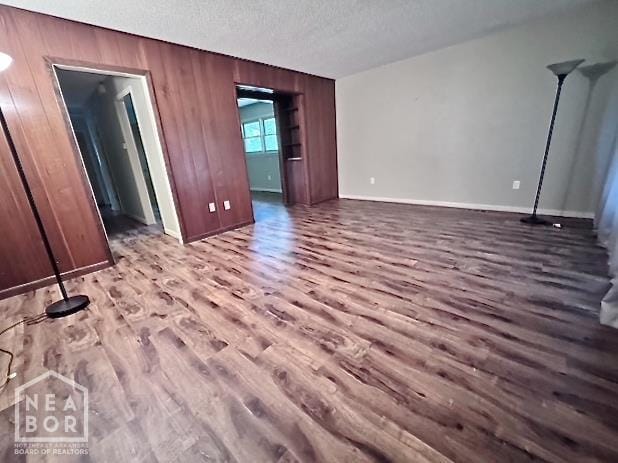 905 Locust Dr, Jonesboro, AR 72401 - empty room featuring wood finished floors, wood walls, a textured ceiling, and baseboards