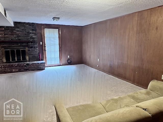905 Locust Dr, Jonesboro, AR 72401 - living room with a textured ceiling, wooden walls, and a brick fireplace