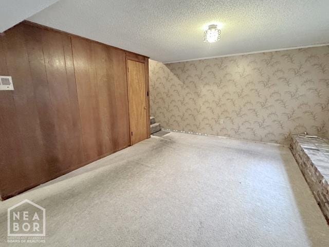 905 Locust Dr, Jonesboro, AR 72401 - additional living space featuring stairway, wallpapered walls, carpet flooring, a textured ceiling, and wood walls