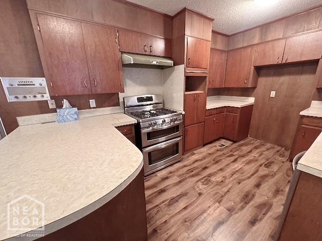 905 Locust Dr, Jonesboro, AR 72401 - kitchen with double oven range, under cabinet range hood, light wood-type flooring, light countertops, and a textured ceiling