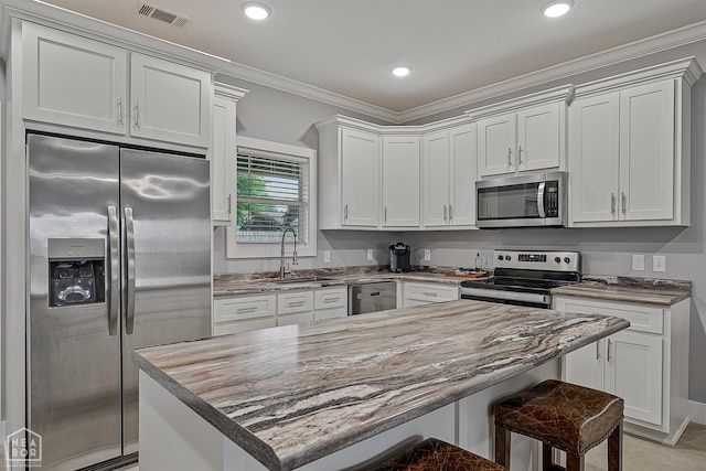 716 Gabe Ln, Manila, AR 72442 - kitchen with stainless steel appliances, ornamental molding, a sink, a breakfast bar, and white cabinets