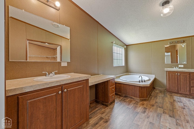 338 Buttercup Ln, Manila, AR 72442 - full bath featuring lofted ceiling, a textured ceiling, two vanities, wood finished floors, and a garden tub