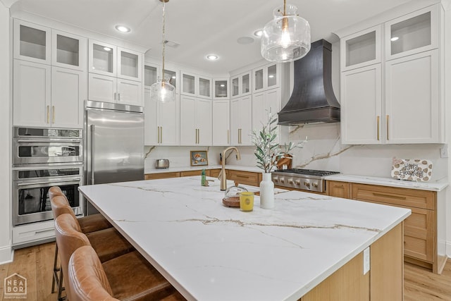 126 County Road 7459, Jonesboro, AR 72401 - kitchen with premium range hood, stainless steel appliances, light wood-style floors, light stone countertops, and pendant lighting