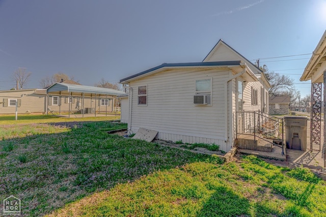 view of side of home with a carport, cooling unit, and a lawn